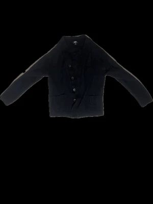 Svart kofta från Uniqlo XS - En svart kofta från Uniqlo i storlek XS. Koftan har långa ärmar, knappar framtill och två fickor. Perfekt att slänga på sig över en t-shirt eller linne. Enkel och stilren design som funkar till det mesta. Råka tvätta den fel så är väldigt liten nu passar ungefär folk som är 160 köpt för 699