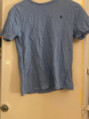 2 par Ralph Lauren tröjor  - Två klassiska t-shirts från Polo Ralph Lauren. En är ljusblå med kort ärm och mörkblå logga på bröstet, den andra är vinröd med lång ärm och blå logga. Båda har rund hals och är gjorda i mjuk bomull som känns skön mot huden. Ni får med båda. 