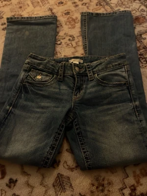 Blå jeans från Gina Tricot, stl 152 - Snygga blå jeans från Gina Tricot i storlek 152. Klassisk femficksmodell med coola detaljer som extra ficka med knapp framtill. Jeansen har raka ben och kontrastsömmar som ger en schysst look. Perfekta till vardagsstilen!