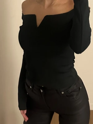 Svart offshoulder topp med v-ringning - Säljer en mörk grön offshoulder topp med lång ärm och snygg v-ringad detalj framtill i storlek S passar även en XS