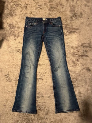 Blå bootcut low waist jeans  - Säljer ett par blå bootcut low waist jeans från Gina Tricot med röda kontrastsömmar och broderade bakfickor💕💕. Jeansen har klassisk femficksmodell, låg midja och är tillverkade i mjukt denimtyg. Snygg tvätt med slitningar framtill och bak. 