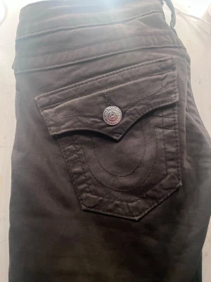 Väldigt lågmidjade jeans   True Religion - Priset är inte satt kom gärna med bud Säljer mina  True Religion väldigt lågmidjade skulle jag säga dom är lite mot de gröna hållet dom är i stolek w26/30 med deras ikoniska ficklock och silverfärgad knapp med logga. Shortsen har en normal passform och är tillverkade i mjuk bomull, perfekta för en avslappnad stil.
