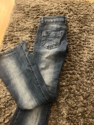 Bootcut jeans med låg midja - Säljer ett par mörkblå bootcut jeans med snygg slitning och låg midja. Jeansen har klassiska, dragkedja och knapp framtill. Materialet är mjukt denim i bomull med lite stretch för skön passform. Pris kan diskuteras 🩷🩷