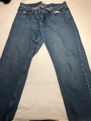 Levi's 501 blå jeans straight fit - Klassiska blåa jeans med rak passform och knappgylf. Jeansen har fem fickor och är tillverkade i slitstarkt bomullsdenim. Perfekta för dig som gillar tidlös stil och vill ha ett par riktigt schyssta jeans i garderoben.