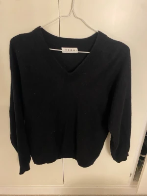 Svart V-ringad stickad tröja Wera - Klassisk svart stickad tröja från Wera med V-ringning och långa ärmar. Tröjan har en enkel och stilren design, perfekt för lager på lager. Mjuk och skön kvalitet som passar till det mesta.