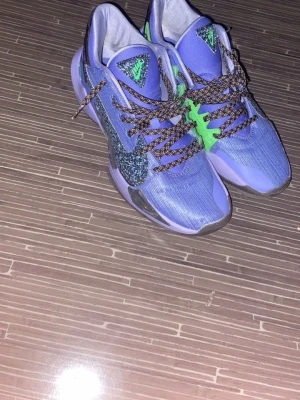 Blå och gröna Nike sneakers - Säljer ett par blå basket sneakers från Nike med gröna detaljer och svartmönstrade skosnören. Skorna har en sportig design med meshmaterial för bra ventilation och en robust sula för extra grepp. Perfekta för dig som vill sticka ut på planen. Använda 2 gånger 