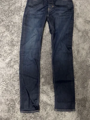 Neuw - Snygga mörkblå jeans från Neuw med klassisk rak passform och gul kontrastsöm. Jeansen har fem fickor och är tillverkade i ett slitstarkt bomullsmaterial. Perfekta för dig som gillar stilrena och tidlösa jeans.