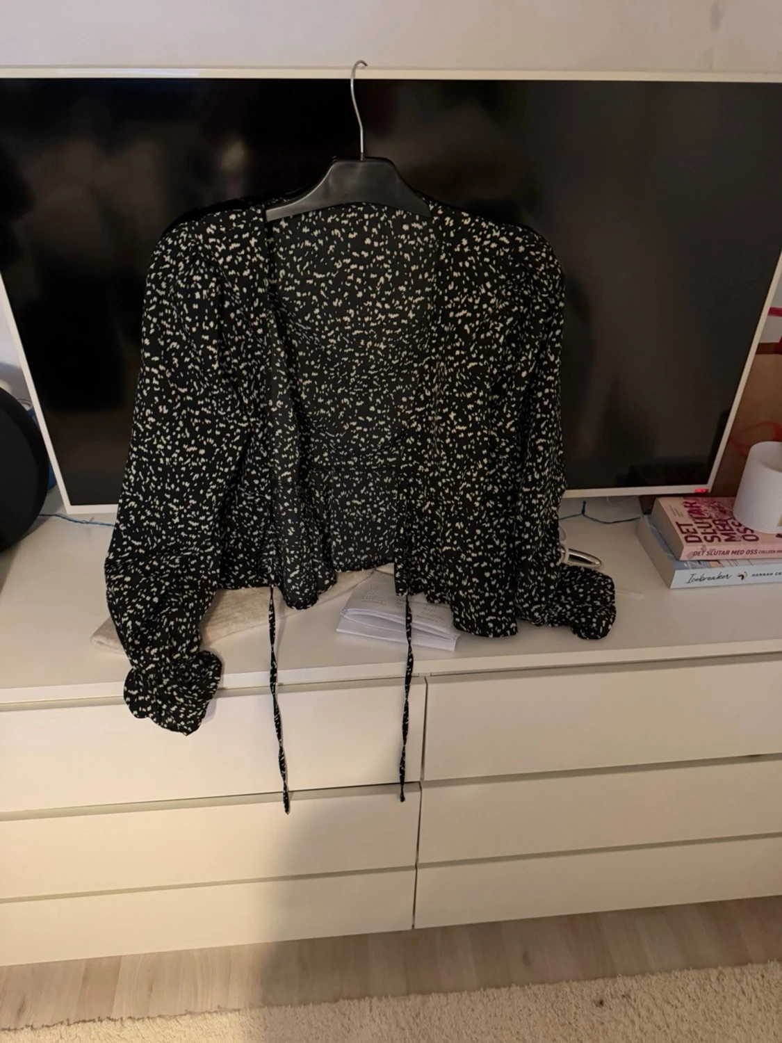 Svart blus med vita blommor och knytband