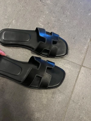 Svarta H tofflor  - Säljer ett par svarta tofflor, aldrig använda 