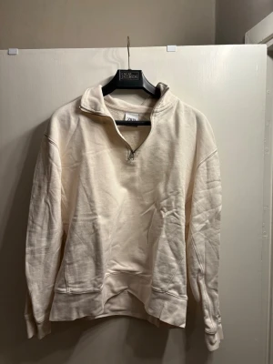 Zara Half-Zip Sweatshirt - Cream/Off-White - Size S - Classic and cozy Zara half-zip sweatshirt in a versatile cream/off-white shade. This piece is perfect for achieving a clean, minimalist look and is easy to style with jeans or joggers.  Condition: Excellent pre-owned condition, used sparingly. Well-maintained with no visible flaws.  Size: Small (S).  Design: Features a high collar with a silver-toned half-zip closure and ribbed cuffs and hem.  Fabric: Soft and comfortable material, perfect for daily wear or lounging.  A great staple for any ward