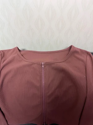 Rosa ribbad sett med dragkedja - Säljer en snygg, ribbad crop top i dammigt rosa med lång ärm och dragkedja framtill. 