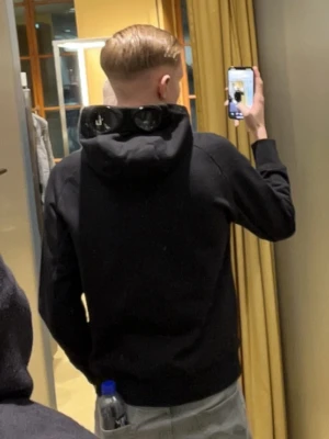 Svart hoodie med dragkedja - Säljer en svart hoodie från C.P Company i storlek S. En av dom skönare tröjor jag äger men säljer pågrund av att jag växt ur den. Inga skador på själva tröjan eller ögonen den är i nyskick då jag växte ur den rätt snabbt. Pris kan diskuteras vid snabb affär