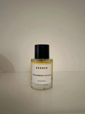 ESSNCE Strawberry Eclair parfym - ESSNCE Strawberry Eclair är en Eau de Parfum i en rund glasflaska med svart lock. Doften har en söt och fruktig karaktär med inslag av jordgubb. Flaskan har en enkel, stilren etikett och innehållet är ljusgult. Perfekt för dig som gillar gourmanddofter.