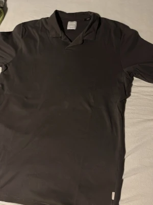 Svart polotopp från Jack & Jones - Klassisk svart polotopp från Jack & Jones Premium. T-shirten har krage och korta ärmar, perfekt för en clean och stilren look. Tillverkad i mjuk bomull som känns skön mot huden. Enkel att matcha med jeans eller chinos.