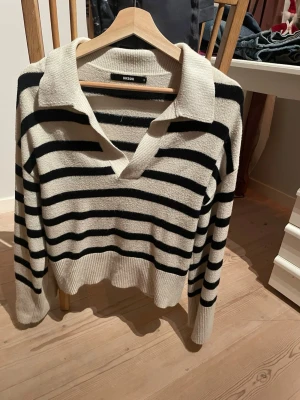 Randig stickad tröja från Bik Bok - Säljer en stickad tröja från Bik Bok med svartvita horisontella ränder. Tröjan har en bred krage och djup v-ringning, samt långa ärmar och ribbade muddar. Perfekt för en avslappnad och trendig look.