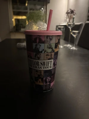 Taylor Swift The Eras Tour mugg - Cool plastmugg med lock och sugrör från Taylor Swift The Eras Tour. Muggen har färgglada rutor med olika bilder på Taylor Swift och texten 'The Eras Tour' på framsidan. Perfekt för dryck på språng eller som samlarpryl för fans.