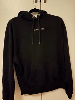 Svart hoodie med text Creative Babe - Svart hoodie med huva och dragsnören, samt broderad vit text 'CREATIVE BABE' på bröstet. Klassisk känguruficka framtill och ribbade muddar vid ärmslut och nederkant. Perfekt för en chill och avslappnad stil.