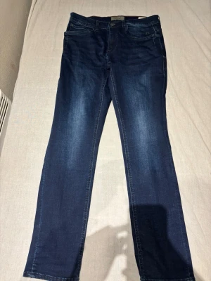 Mörkblå blends jeans regular fit - Snygga mörkblå jeans från Diesel med klassisk femficksdesign och raka ben. Jeansen har diskreta slitningar framtill och bakfickor med enkel söm. Tillverkade i slitstarkt denim-material som ger en skön passform.