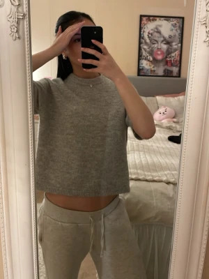 Grå stickad tröja från Gina Tricot - Mysig grå stickad tröja från Gina Tricot med rund halsringning och rak, något kortare passform. Tröjan har ribbstickade muddar vid hals, ärmslut och nederkant. Perfekt för lager-på-lager och enkel att matcha.