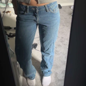 Blå raka jeans med låg midja - Säljer ett par klassiska blå jeans med låg midja och raka ben. Jeansen har fem fickor och stängs med knapp och dragkedja. Perfekta för en avslappnad och cool stil.