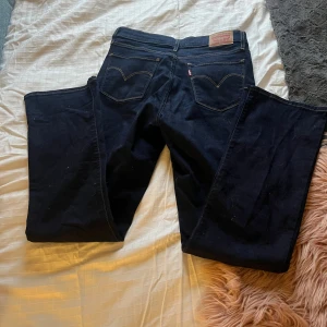 Levi's 315 Shaping Bootcut jeans blå - Säljer ett par mörkblå Levi's 315 Shaping Bootcut jeans med klassiska bakfickor och snygga kontrastsömmar. Modellen har bootcut-ben och normal midja, tillverkade i stretchig denim för en bekväm passform. Säljs då dom ej används, har aldrig använt dom. Pris går att diskuteras 💞