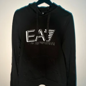 Emporio Armani hoodie svart - Emporio Armani hoodie i bra skick men texten i framsidan saknas lite, pm vid intresse.
