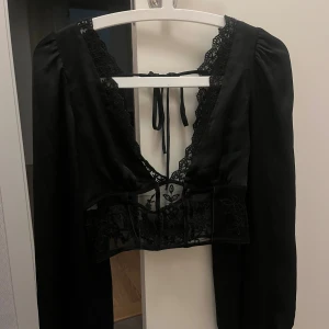 Satin blus med spets  - Otroligt fin satin blus med spets och blommiga detaljer. Har öppen rygg som knyts ihop och en dragkedja på sidan. Väldigt bra skick! Inga defekter.  Normal i storleken.