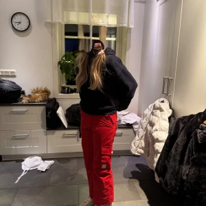 Röda cargopants med fickor - Säljer ett par röda skidbyxor med flera praktiska fickor på sidorna och bak. Byxorna har raka ben och sitter skönt i midjan. Perfekta för dig som gillar en avslappnad och cool stil. Materialet är tåligt och passar bra till utomhusaktiviteter.