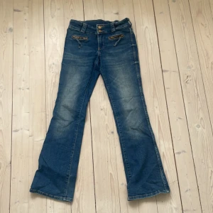 Blå low waist bootcut jeans - Snygga blå bootcut jeans från H&M med låg midja och justerbar midja. 