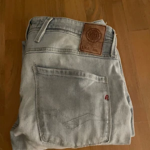 Replay Anbass ljusblå jeans, stl 31 - Säljer ett par ljusblå Replay Anbass jeans i klassisk femficksmodell. Jeansen har en slim passform och raka ben, tillverkade i mjukt denimtyg. Perfekta för dig som gillar en stilren och avslappnad look.
