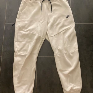 Vit Nike tech byxor - Tjena, Säljer ett par vita nike tech byxor. Använda:2-3 gånger. Äkta i storlek L. True to Size, Säljer dessa för de var ganska stora men säljer för ett riktigt bra pris. Hör av er vid intressen. Fraktar inom 1-2 dagar😀