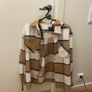 Beige/brun overshirt - Superfin overshirt i beige, vitt och brunt rutmönster från FSBN. Mjuk och varm, perfekt som lätt jacka på hösten eller som skjorta inomhus. Använd endast ett fåtal gånger, i mycket fint skick utan fläckar eller slitage.