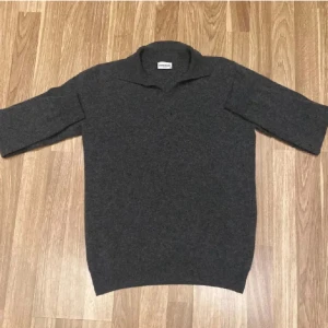 Mörkgrå polotröja från John Henric - Snygg mörkgrå polotröja från John Henric i storlek S. Tröjan är tillverkad i en lyxig mix av 90% ull och 10% kashmir, har krage och trekvartsärm. Perfekt för dig som gillar stilrena och mjuka plagg med exklusiv känsla.