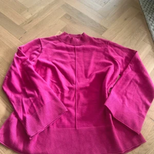 Ceriserosa stickad tröja Indiska S - Säljer en ceriserosa stickad tröja från Indiska i storlek S. Tröjan har ribbade muddar vid ärmslut, nederkant och hals, samt en rak passform och lång ärm. Perfekt för dig som vill ha en färgklick i garderoben!