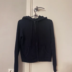 mörkblå stickad hoodie  - mörkblå stickad hoodie från Brandy Melville med dragkedja framtill och två fickor. Tröjan har huva, ribbade muddar och lång ärm. Perfekt för dig som gillar en chill och enkel stil. 