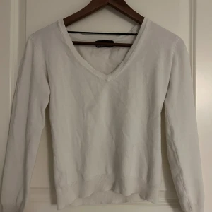 Vit v-ringad tröja från Vero Moda - Klassisk vit v-ringad tröja från Vero Moda. Tröjan har lång ärm, ribbade muddar och är i mjukt material som passar perfekt till lager-på-lager. Enkel och stilren design som funkar till allt. Säljer då den inte kommer till användning