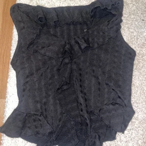 Svart volangblus från Vero Moda - Supersnygg svart blus från Vero Moda med volangdetaljer längs halsringningen. Helt oanvänd med lapp kvar på!