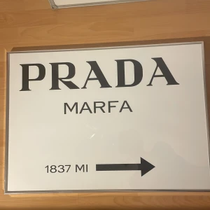 PRADA tavla - Stilren poster med texten 'PRADA MARFA'. Perfekt för dig som vill ge ditt rum en trendig och modern känsla med modevibbar. 
