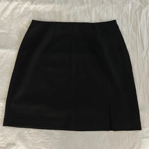 Svart minikjol från Object, strl 36 - Svart, stilren kortkjol från Object i storlek 36. Kjolen har en diskret slits nertill, resår på insidan i midjan och en dold dragkedja i sidan. Aldrig använd. 