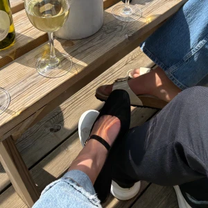 Svarta ballerinaskor med rem från H&M - Svarta ballerinaskor från H&M med fyrkantig tå och smal rem över foten. Skorna är i mockaimitation och har en platt sula. Perfekta för en stilren och enkel look, passar till både jeans och klänning.