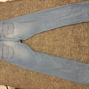 Levi's 501 ljusblå jeans straight fit - Klassiska Levi's 501 jeans i ljusblå denim med raka ben och normal passform. Byxorna har fem fickor, knappgylf och den ikoniska läderpatchen bak i midjan. Perfekta för en avslappnad och tidlös stil. Strl W32 L32