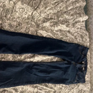 Mörkblå bootcut jeans med stretch - Snygga mörkblå jeans med bootcut passform och klassiska femficksdetaljer. Jeansen har en låg midja och är gjorda i stretchigt denimtyg.