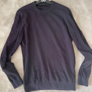 Mörkblå stickad tröja Massimo Dutti - En stilren mörkblå stickad tröja från Massimo Dutti med rund halsringning och ribbade muddar. Perfekt för lager-på-lager och funkar lika bra till jeans som till chinos. Enkel och klassisk design som passar till många olika looks.