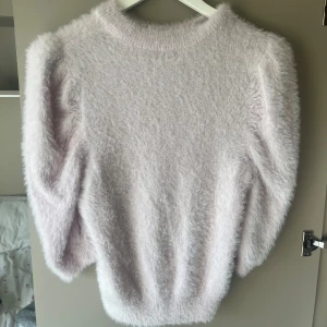 Ljusrosa fluffig stickad tröja VRS XS - Supermjuk och fluffig ljusrosa stickad tröja från VRS i storlek XS. Tröjan har lång ärm och en klassisk rund halsringning. Perfekt för dig som vill ha en cozy vibe och gillar pastelliga färger.