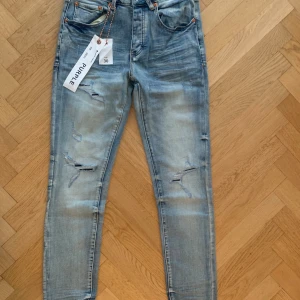Ljusblå ripped jeans från Purple Brand - Snygga ljusblå jeans från Purple Brand med slitna detaljer och ripped look på benen. Jeansen har slim passform.