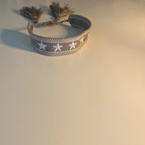 Grått armband med vita stjärnor som är hemmagjort!!! - Snyggt grått tygarmband som jag har gjort ensam hemma!!! Med lite hjälp av min mamma… Säljer ett för 100kr och två för 150kr!!! Skriv för med frågor!🙂