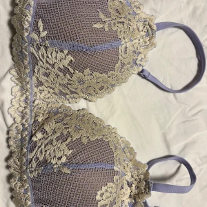 Ljuslila spets-BH Intimissimi - Superfin ljuslila bh Intimissimi med tunna justerbara axelband och vackra blommiga spetsdetaljer i beige. Kuporna är lätt vadderade. Ej bygel. Helt ny och oanvänd. Säljes pga felköp. Storlek 75B