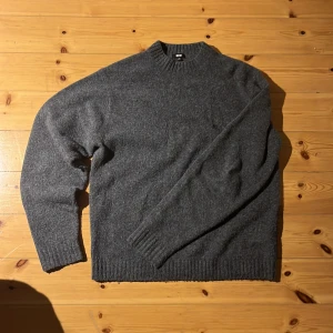 Mörkgrå stickad tröja från Uniqlo - Mysig mörkgrå stickad tröja från Uniqlo i storlek S. Tröjan har rund halsringning, ribbade muddar och är tillverkad i en blandning av ull, akryl, polyester och elastan. Om jag minns rätt heter den souffle yran crewneck🙏