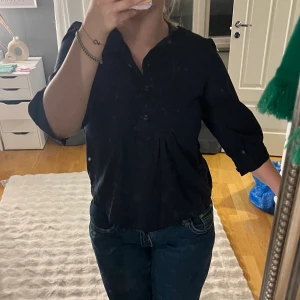 Svart henley från GAP, storlek S - Svart henley-skjorta från GAP i storlek S. Skjortan har trekvartsärm, knappar framtill och en avslappnad passform. Tillverkad i mjuk bomull, perfekt för en chill och stilren look.