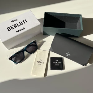 Berluti solglasögon - Snygga solglasögon från Berluti. Bågarna är i en djup blå färg och har diskreta silvriga detaljer vid gångjärnen. Kommer med originaletui och putsduk. Perfekt accessoar för att lyfta din stil.💙🦕